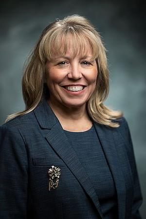 Picture of woman with blond hair a big smile and a black suit.